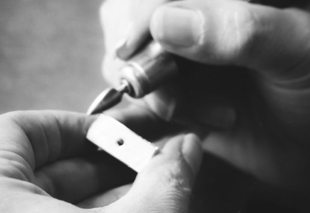 Zwei Hände in Nahaufnahme bearbeiten ein Material mit einem Bohrer